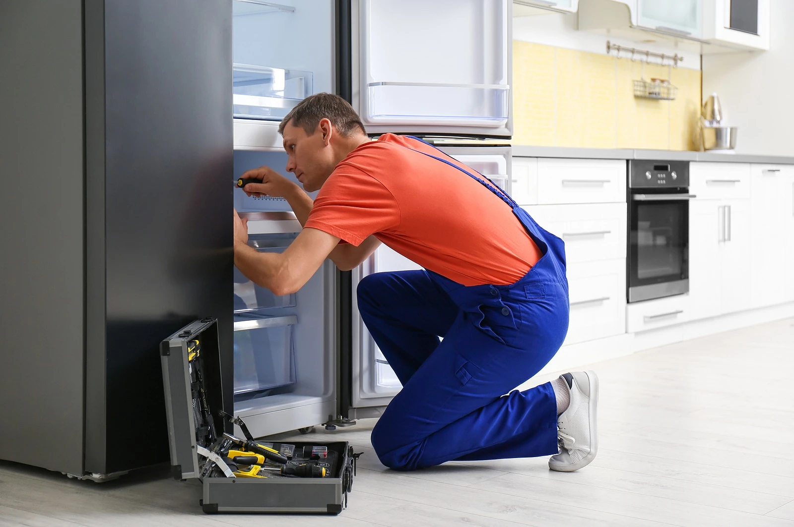 Technician repairing the inside of a refrigerator in a home kitchen